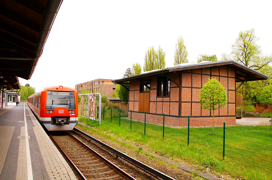 Der Güterschuppen vom Bahnhof Hamburg Klein Flottbek mit einer S-Bahn der Baureihe 474