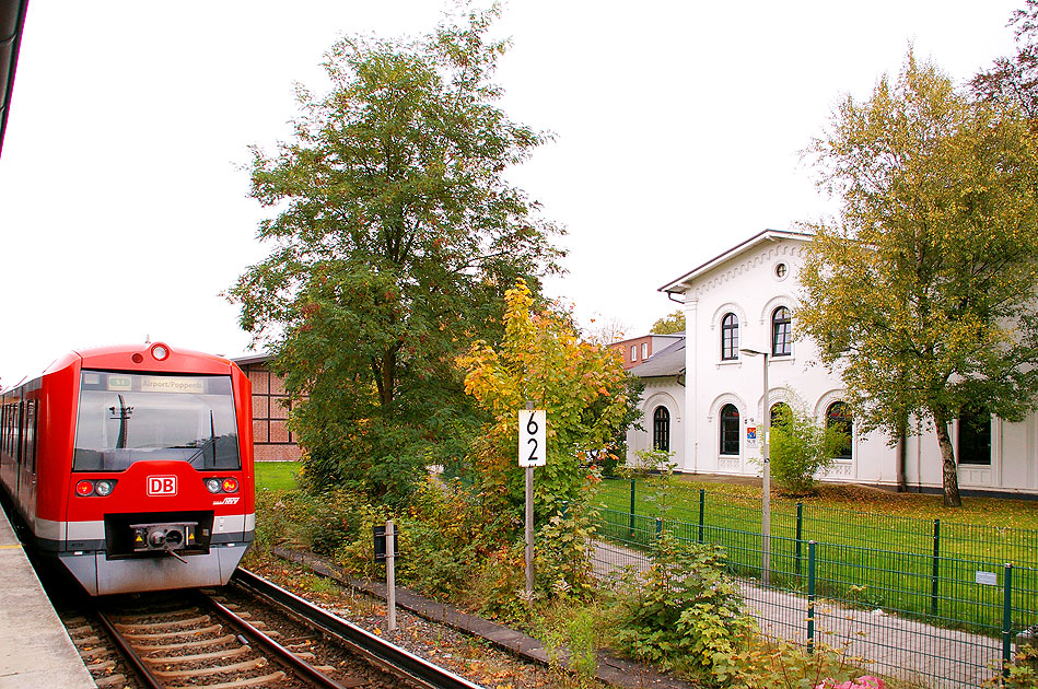 Eine S-Bahn der Baureihe 474 im Bahnhof Klein Flottbek mit dem Bahnhofsgebäude