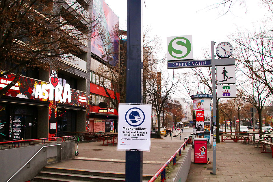 Ein Bahnhofsschild vom Bahnhof Reeperbahn mit Schild zur Masskenpflicht